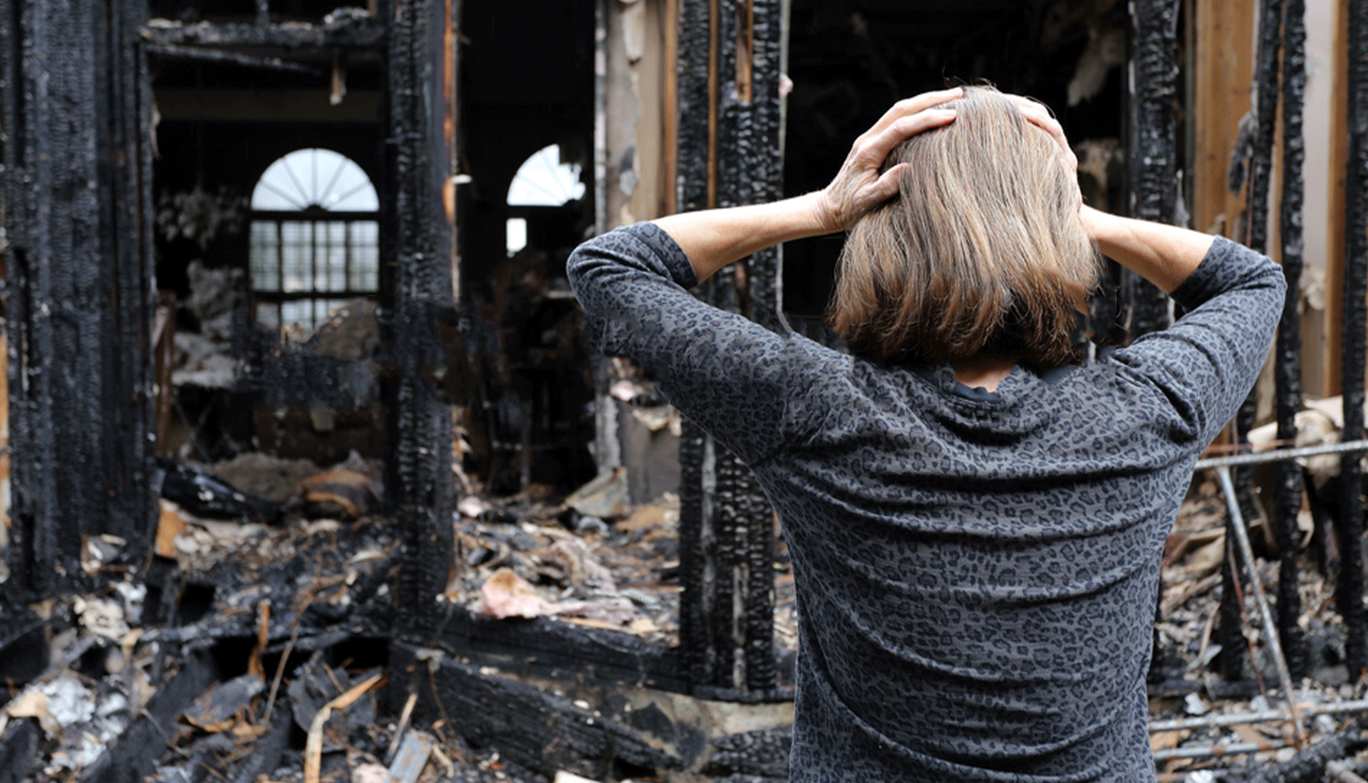 woman in front of house with fire damage
